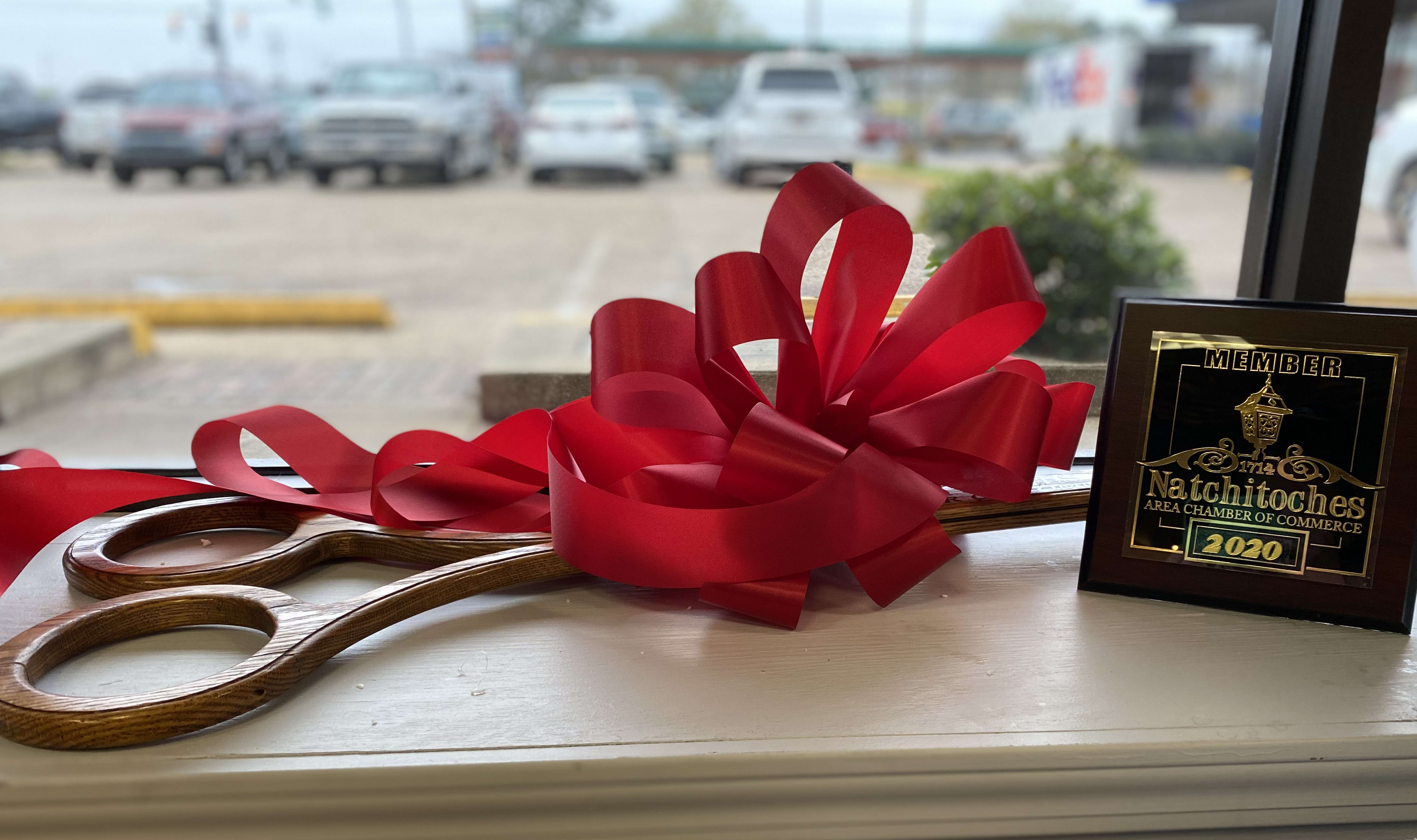 Natchitoches Chamber of Commerce Membership plaque beside large ribbon-cutting ceremonial scissors with a large red bow on top